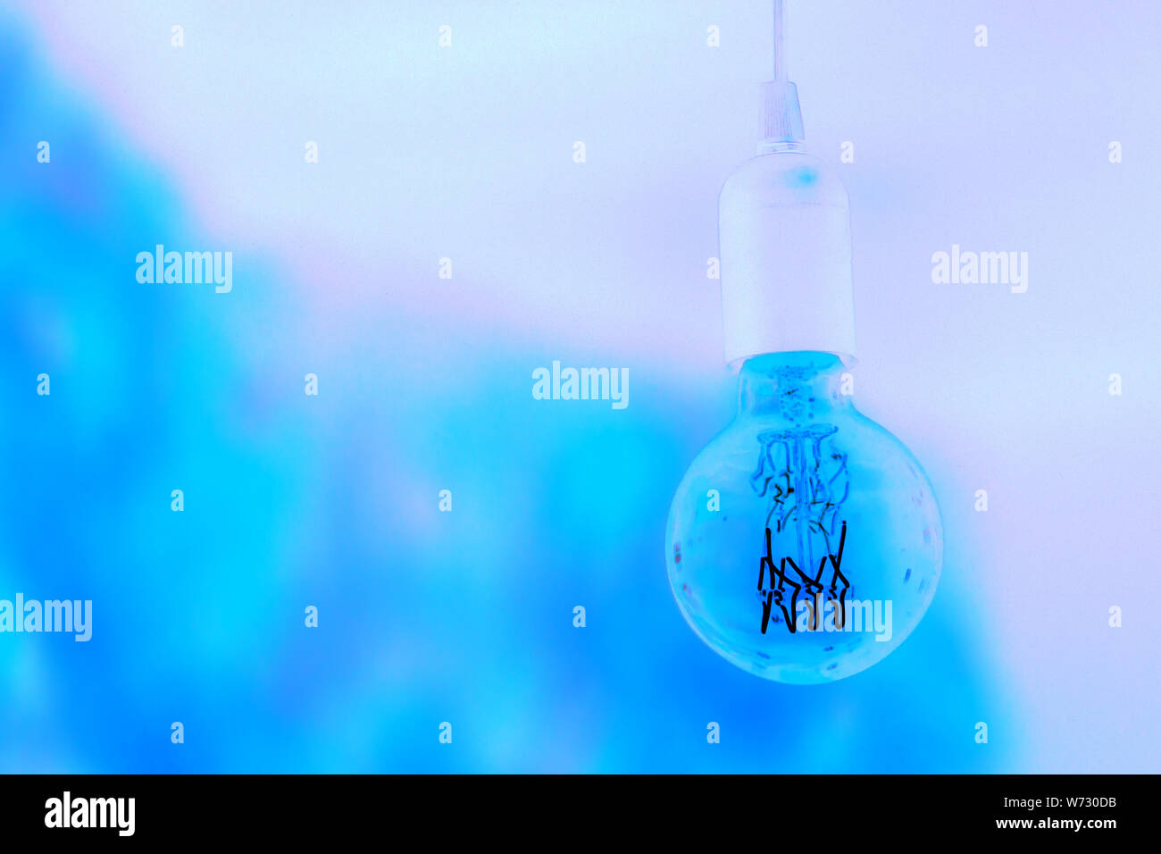 Close up negative image of a retro electric lamp on blueish purple background. New energy concepts Stock Photo