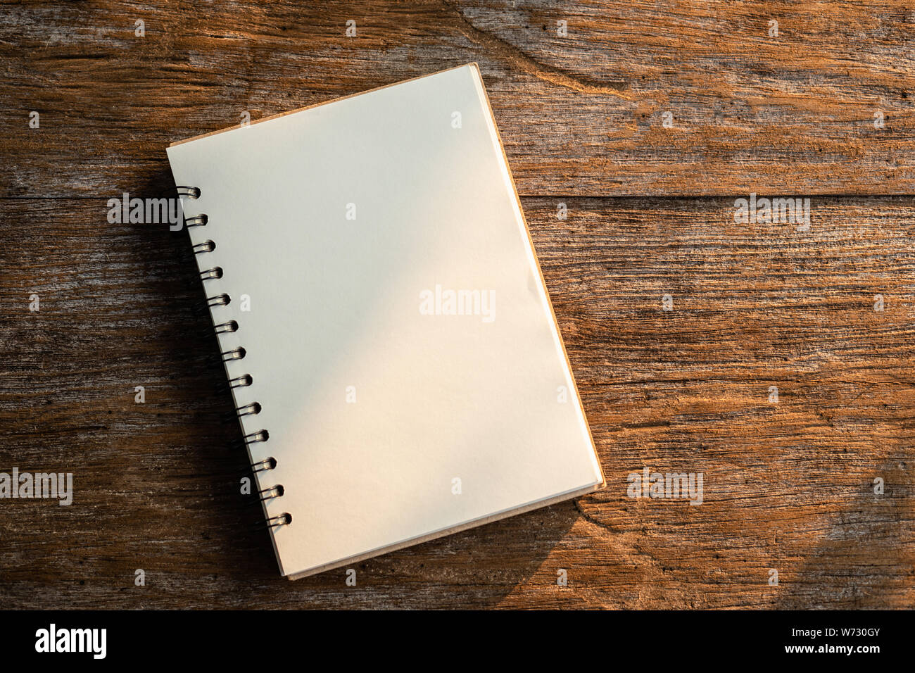 Top view of white book on old wooden plank background with morning nature sunlight Stock Photo