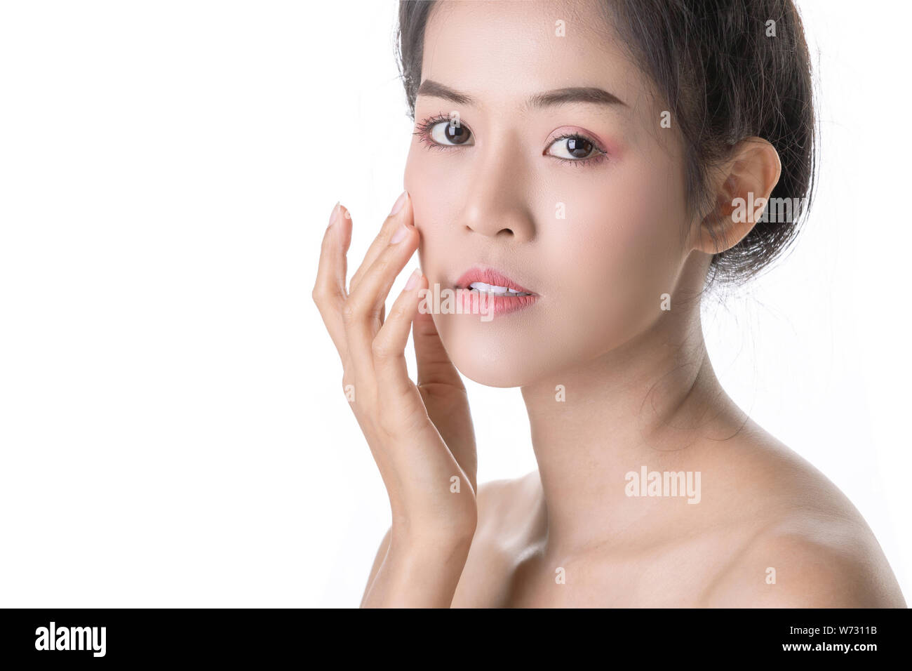 Beautiful Young Asian Woman with Cosmetic on own face. Cosmetologist, Skin care or Beauty concept. Studio shot and isolated on White background Stock Photo