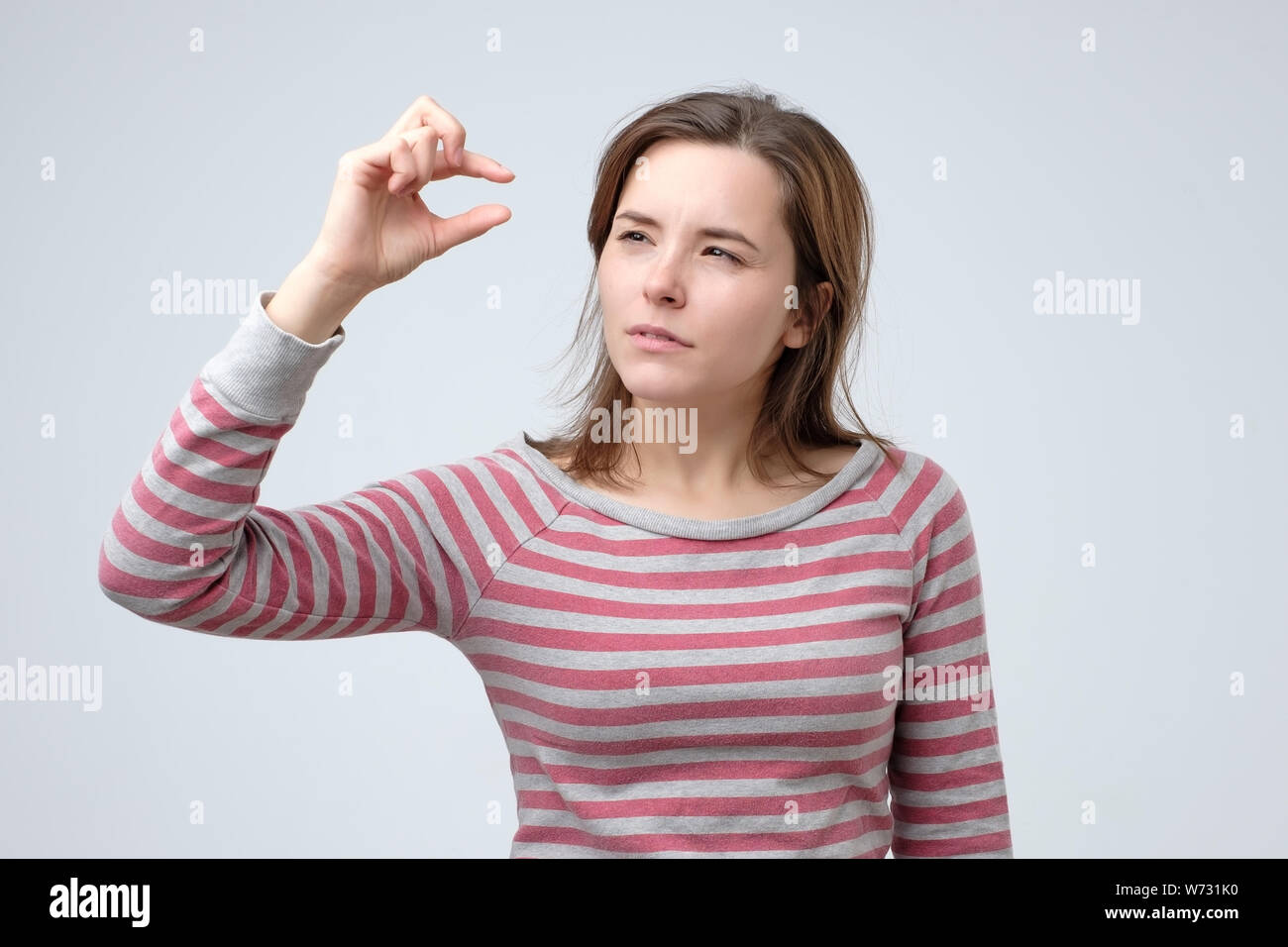Caucasian young woman showing something small and tiny with gesture and ...