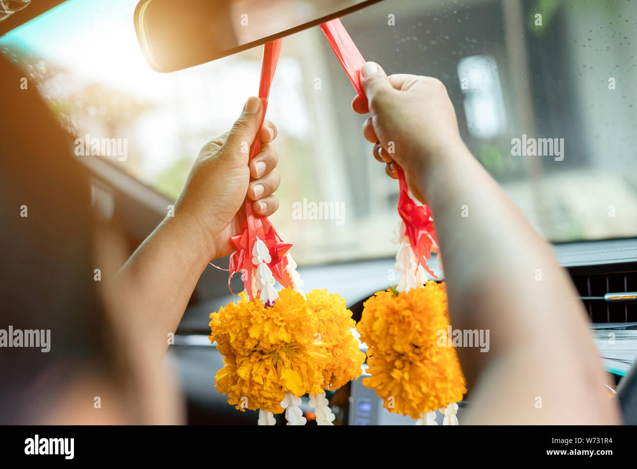 Thai woman with yellow flower garland in hand and praying in the new car for lucky, safety in Thai style Stock Photo