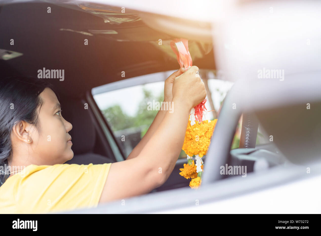 Thai woman with yellow flower garland in hand and praying in the new car for lucky, safety in Thai style Stock Photo