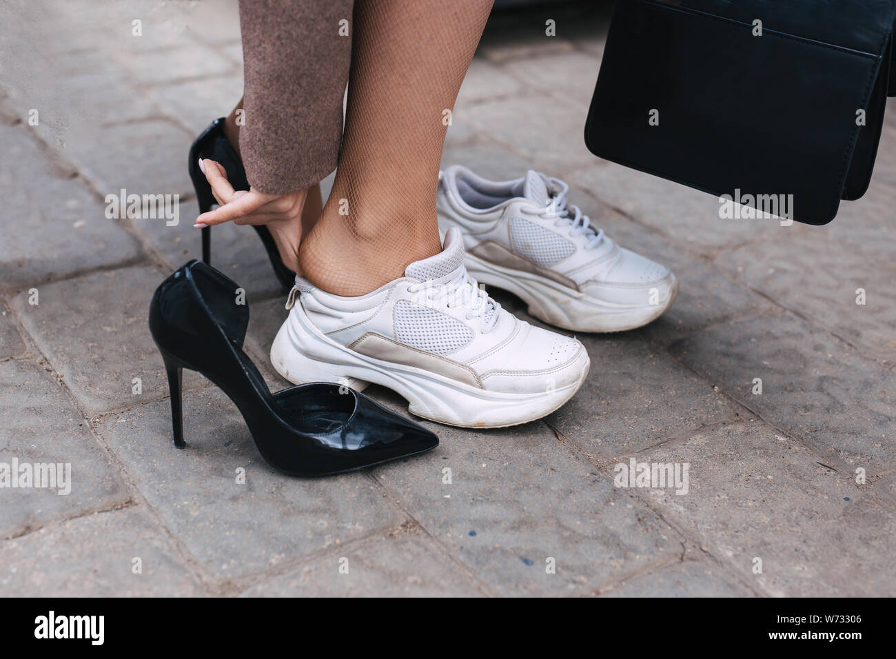 Barefoot business woman shanging shoes from high heel to comfortable sneaker Stock Photo