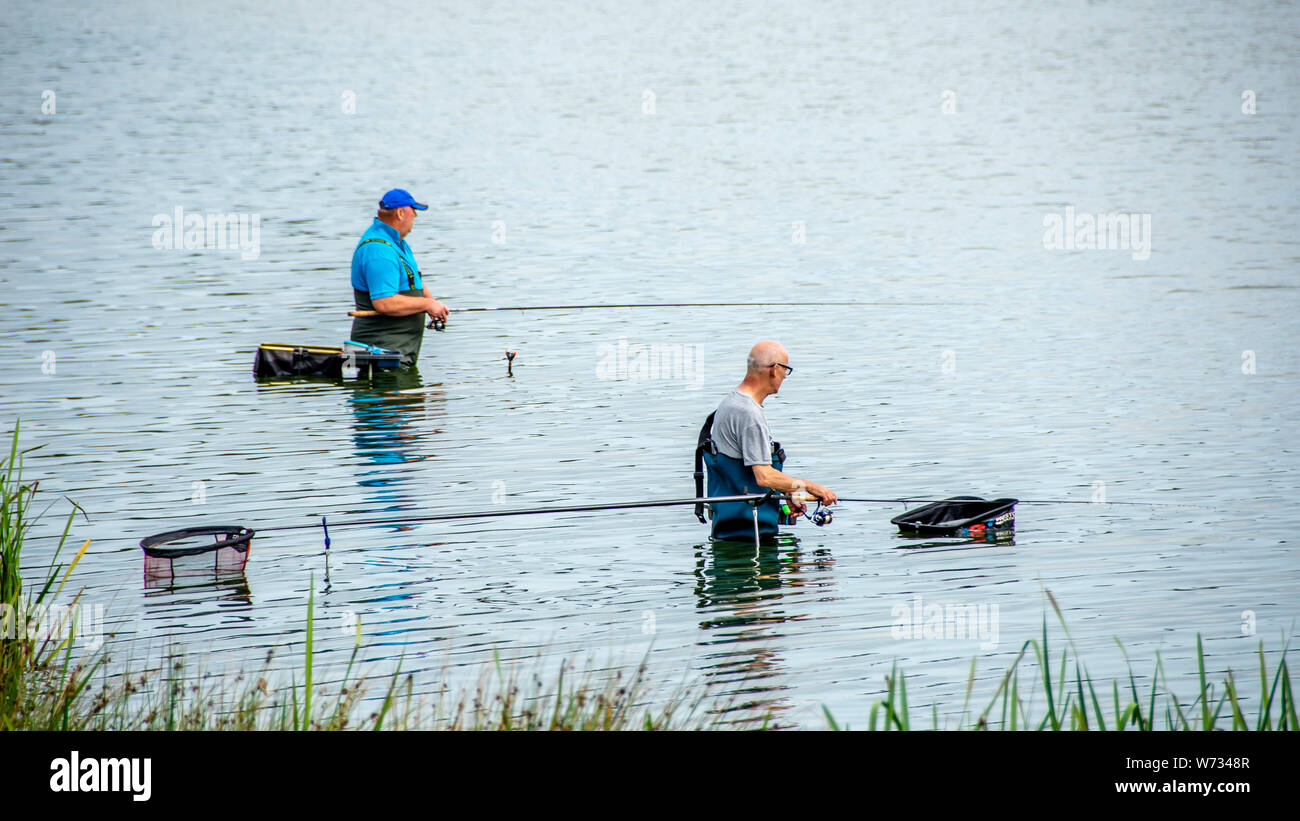 two men fishing with waders on in a lake Stock Photo