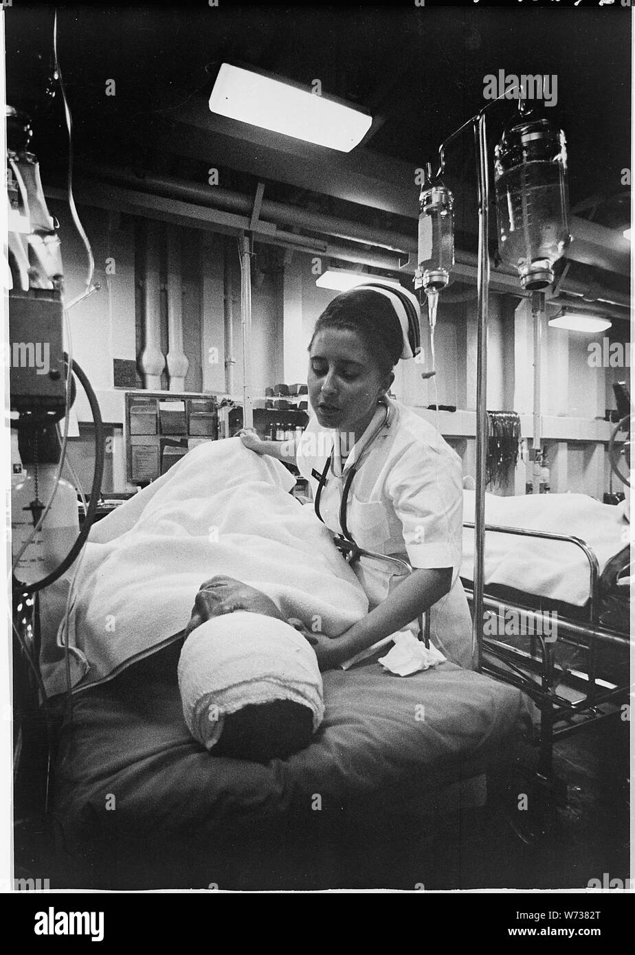 South China Sea....A nurse tends a patient just out of surgery in the intensive care ward of the hospital ship USS Repose (AH-16). The ship is steaming off the coast of Vietnam a few miles south of the 17th parallel. Stock Photo