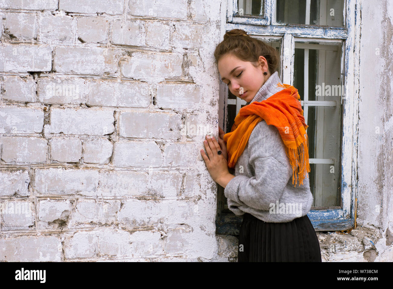 Young woman with orange scarf on old white bricks wall as background ...