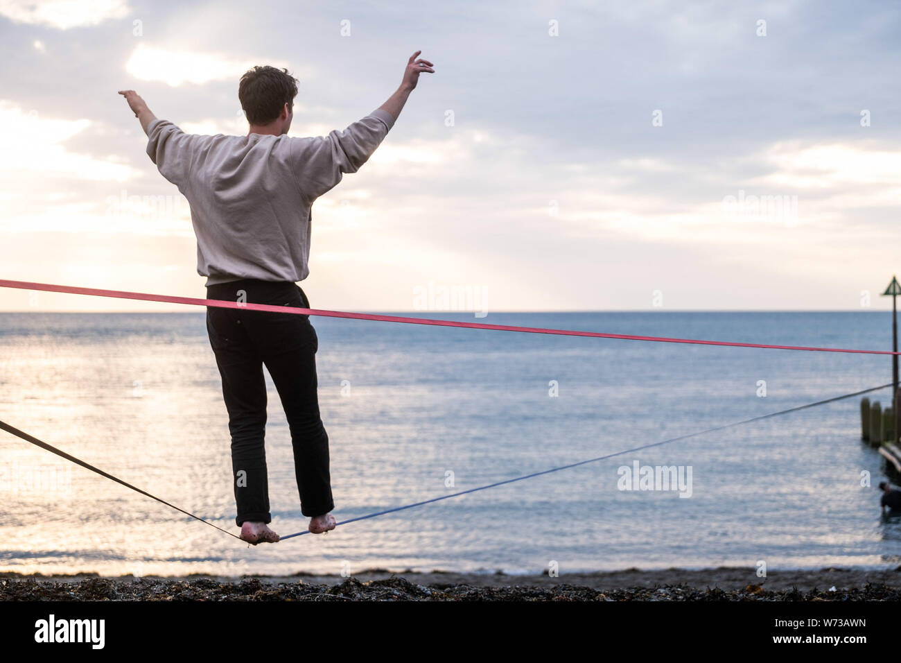 Aberystwyth, Wales, UK. 4th Aug 2019. A young man practices his slackline balancing techniques at  the seaside in Aberystwyth , at the end of a warm but unsettled day on the west wales coast. Photo credit Keith Morris / Alamy Live News Stock Photo