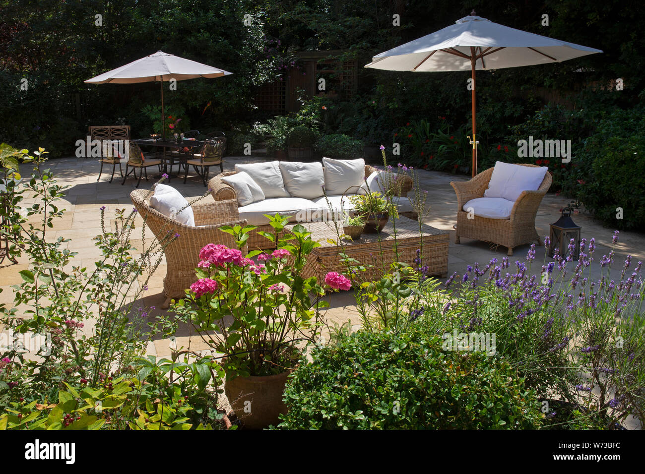 wicker outdoor seating with sun umbrella in English garden, England Stock Photo