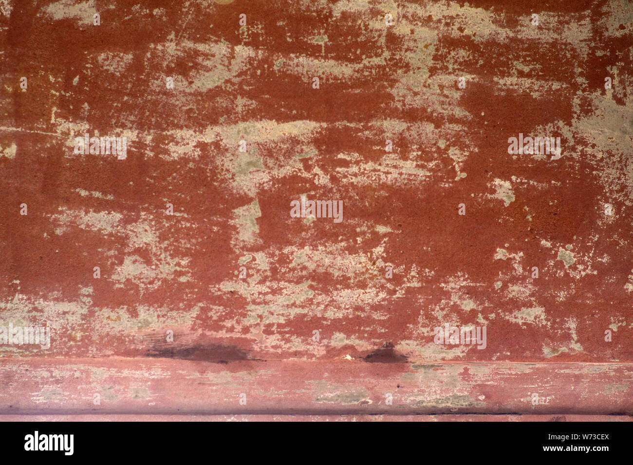 The closeup of peeling clay colored wall paint on a wall Stock Photo
