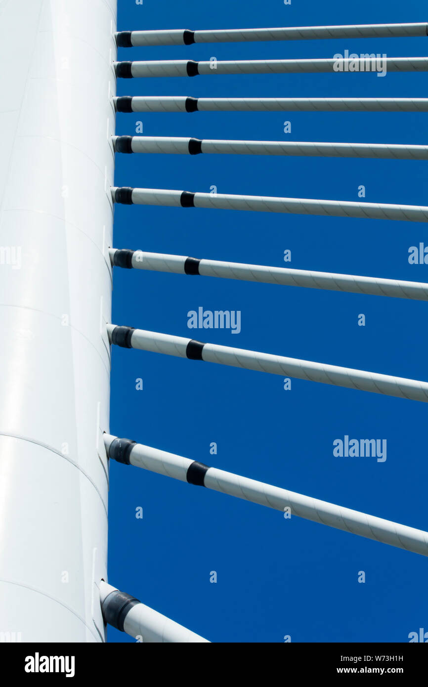 Section of white steel tower and white steel cables of a suspension bridge in low angle view image beneath clear blue sky. Stock Photo