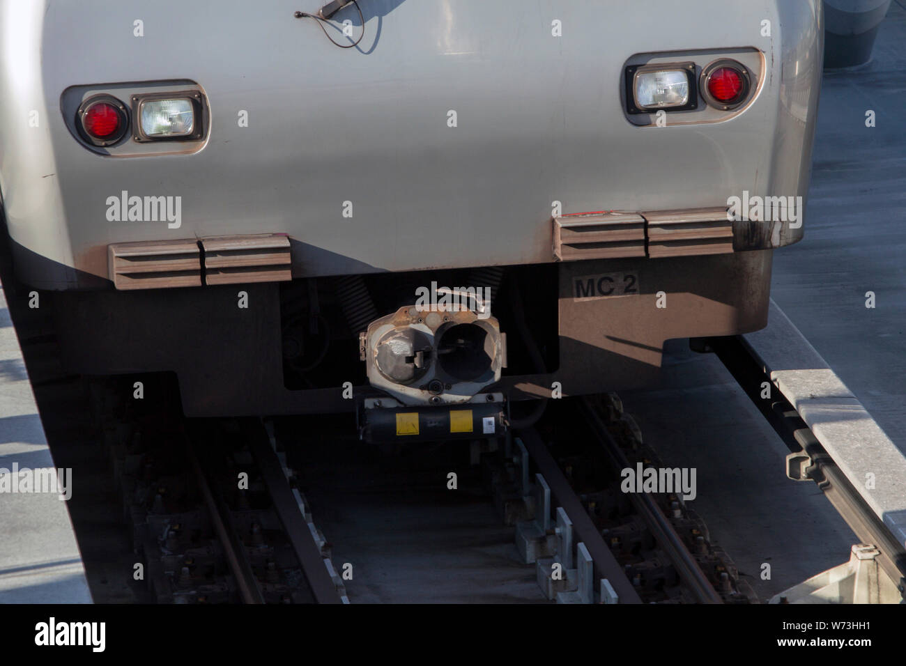 Close up of a metro train's driver cabin's nose without the cabin window. Power line seen next to rails. Stock Photo