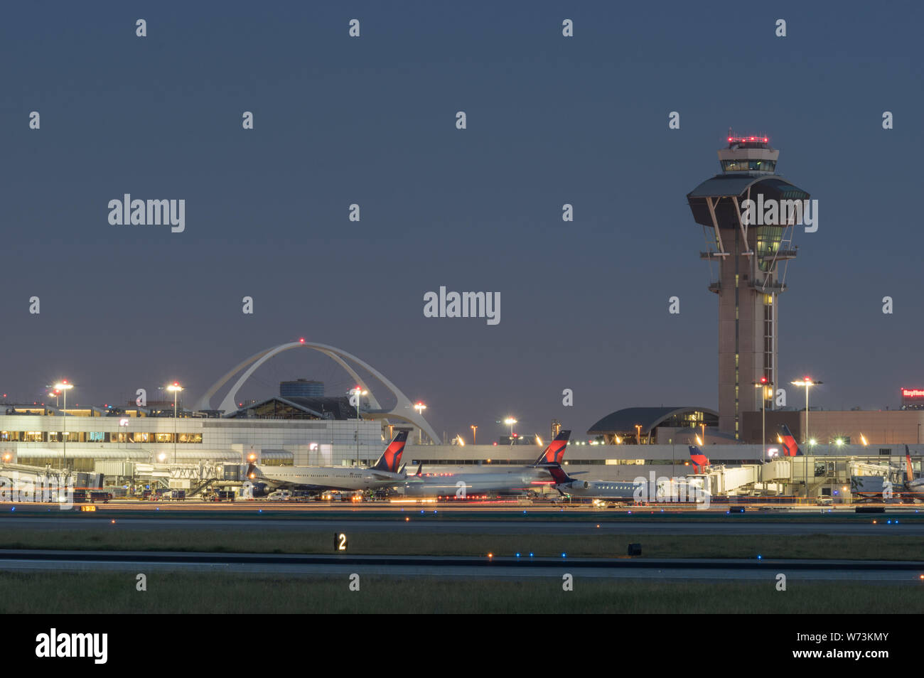 Image of the Theme Building, control tower, and Delta Air Lines jets at the gate, in the Los Angeles International Airport, LAX, at dusk. Stock Photo