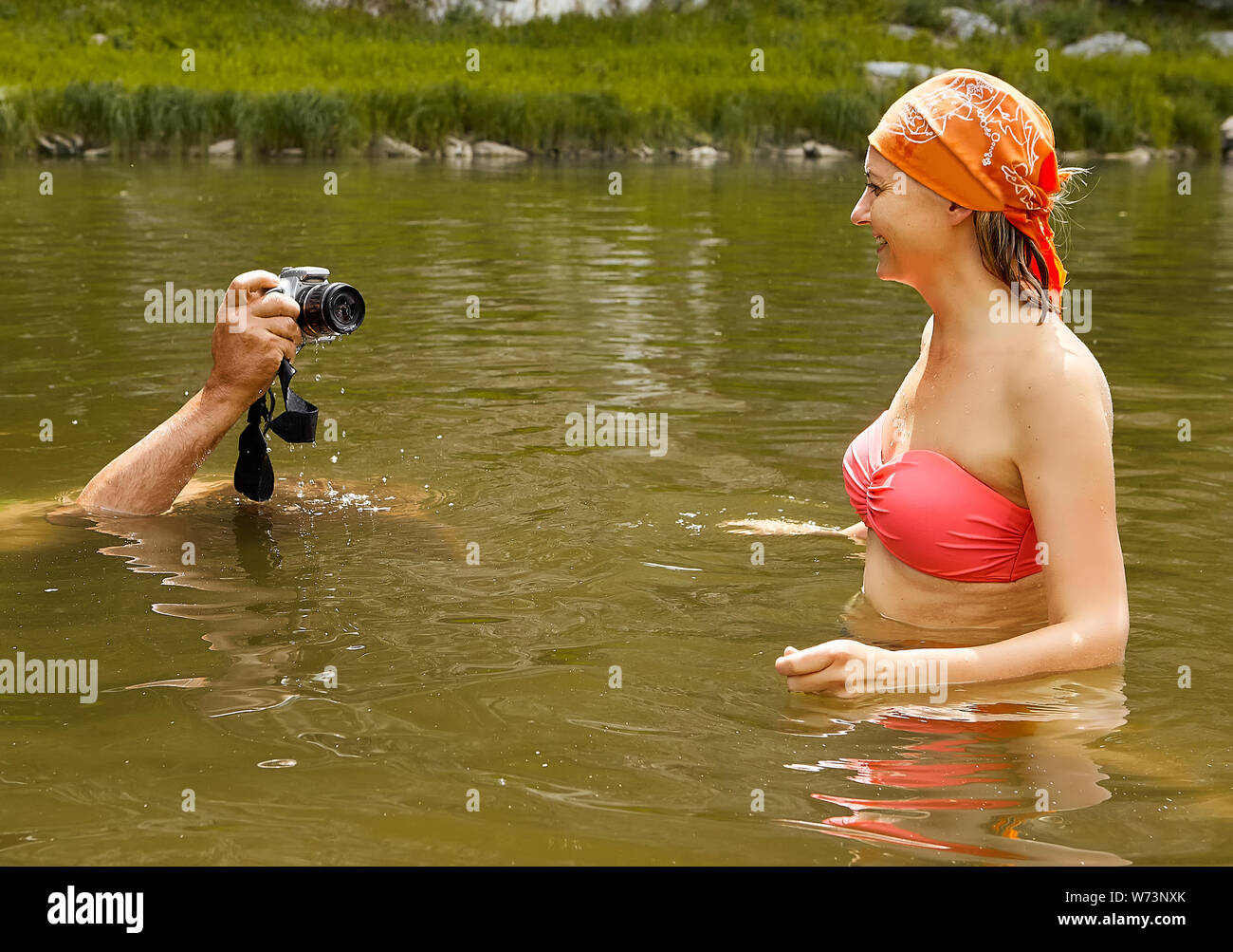 Man is taking pictures of young beautiful smiling wet woman in