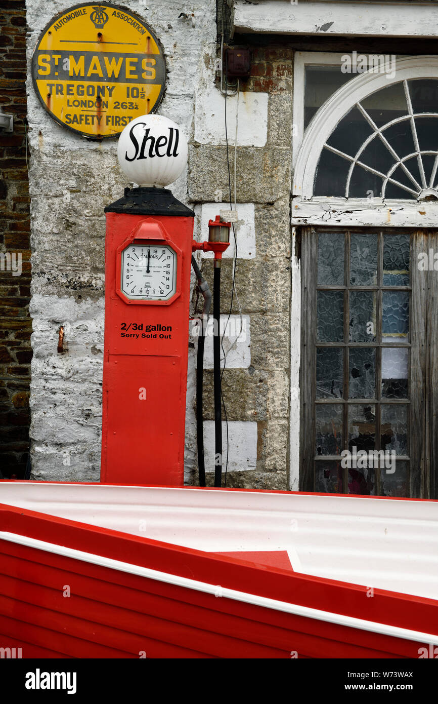 Old gas pump with red boat at weathered stone house in St Mawes Truro Cornwall England Stock Photo
