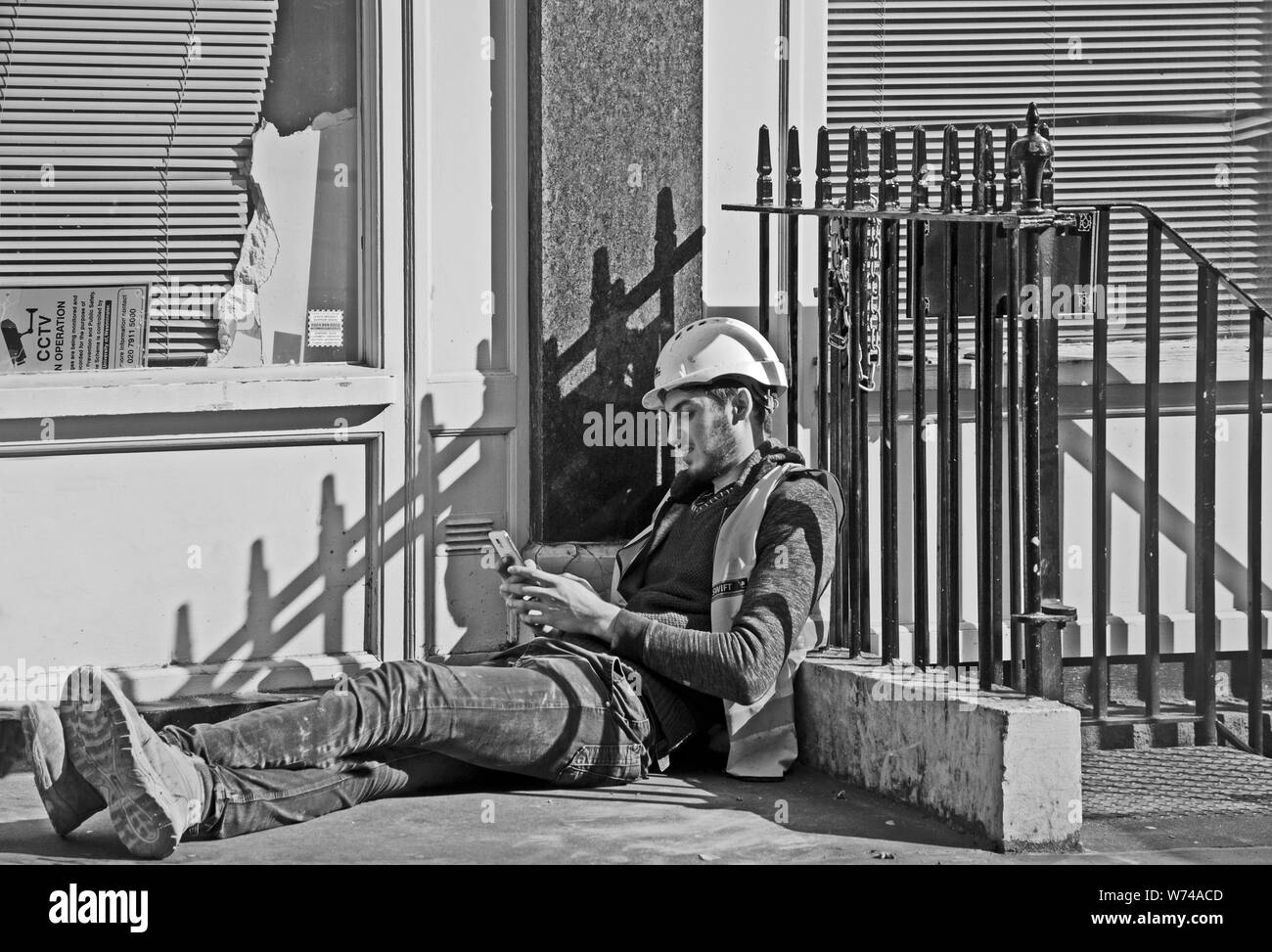 Workman relaxes in the sun at lunch-time, Charlotte Street, London, England, UK Stock Photo
