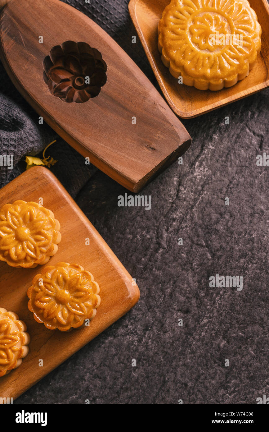 Mid-Autumn Festival traditional food concept - Beautiful Moon cake on black slate table with tea, pastry mold, flower, top view, flat lay, copy space Stock Photo