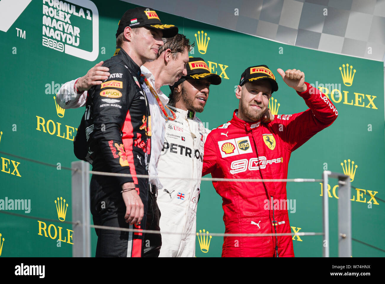 (From L) Red Bull Racing’s Dutch driver Max Verstappen, Mercedes AMG Petronas F1 Team’s chief strategist James Vowles, Mercedes AMG Petronas F1 Team’s British driver Lewis Hamilton and Scuderia Ferrari’s German driver Sebastian Vettel pose for photos on podium after the Hungarian F1 Grand Prix race at Hungaroring. Stock Photo