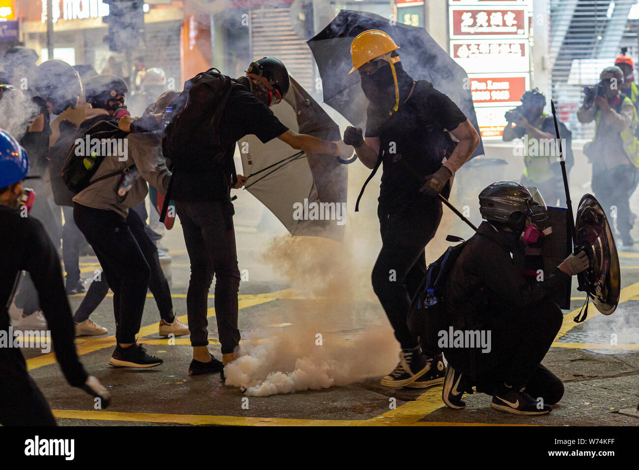 Protesters trying to put out tear gas bombs thrown by police during protests against the extradition bill in Hong Kong.Pro-democracy protesters have continued weekly rallies on the streets of Hong Kong against a controversial extradition bill since June 9, as the city plunged into crisis after waves of demonstrations and several violent clashes. Hong Kong's Chief Executive Carrie Lam apologized for introducing the bill and declared it 'dead', however protesters have continued to draw large crowds with demands for Lam's resignation and completely withdraw the bill. Stock Photo