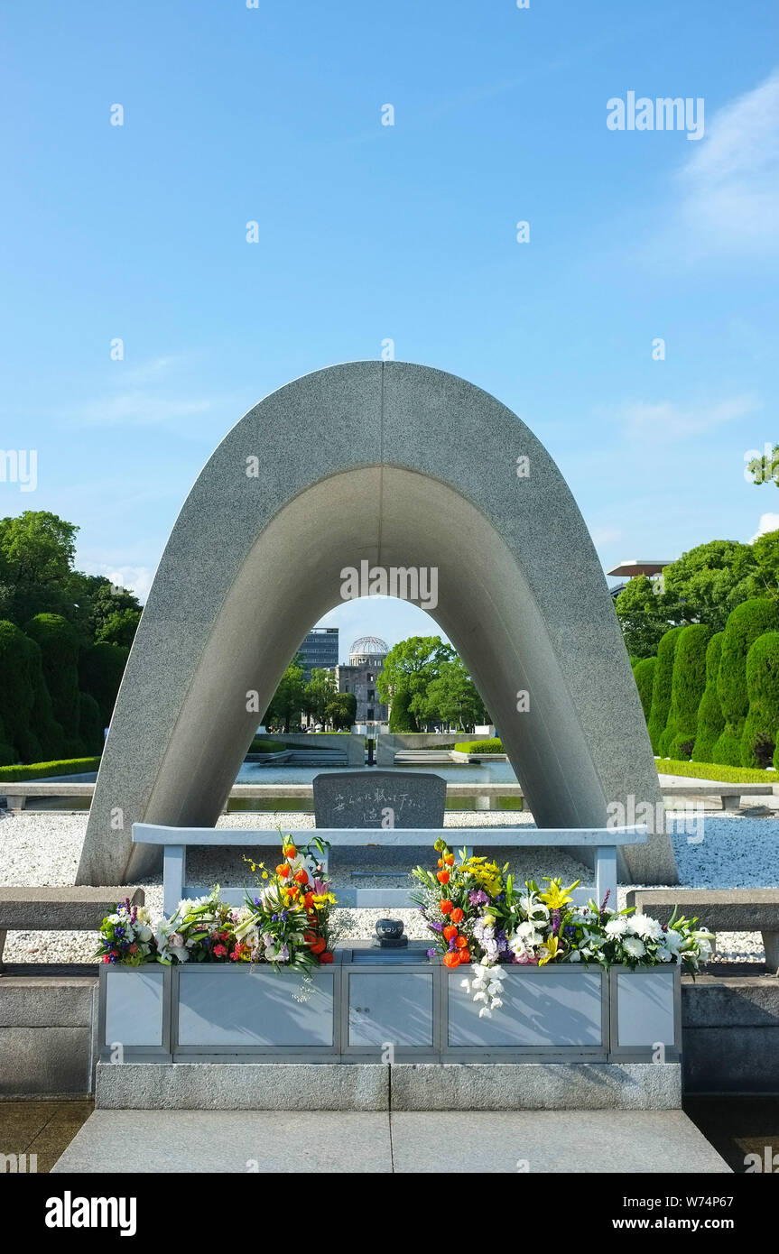 The Memorial Cenotaph with the A Bomb Dome in the background, in the Peace Memorial Park in Hiroshima, Japan. Stock Photo