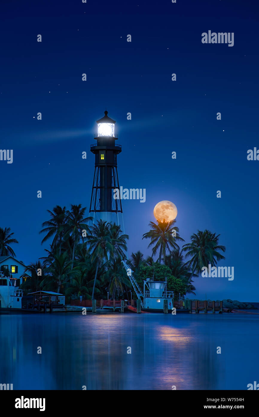 A beautiful full moon rises at the Hillsboro Inlet Lighthouse in South Florida. It is a historical landmark and was first lit in 1907. Stock Photo