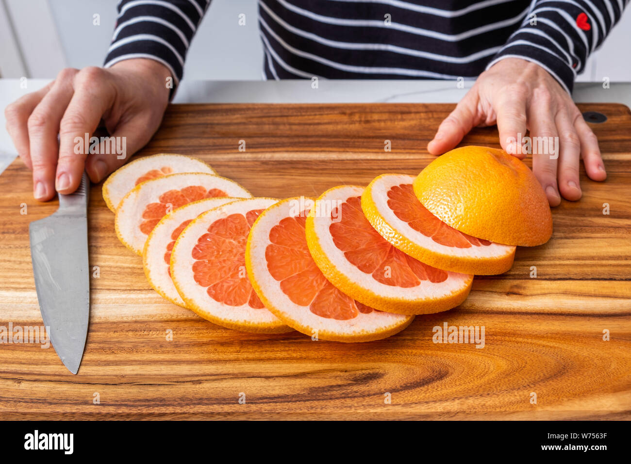 https://c8.alamy.com/comp/W7563F/caucasian-woman-hands-placed-on-wooden-chopping-board-with-sliced-red-grapefruit-and-knife-W7563F.jpg
