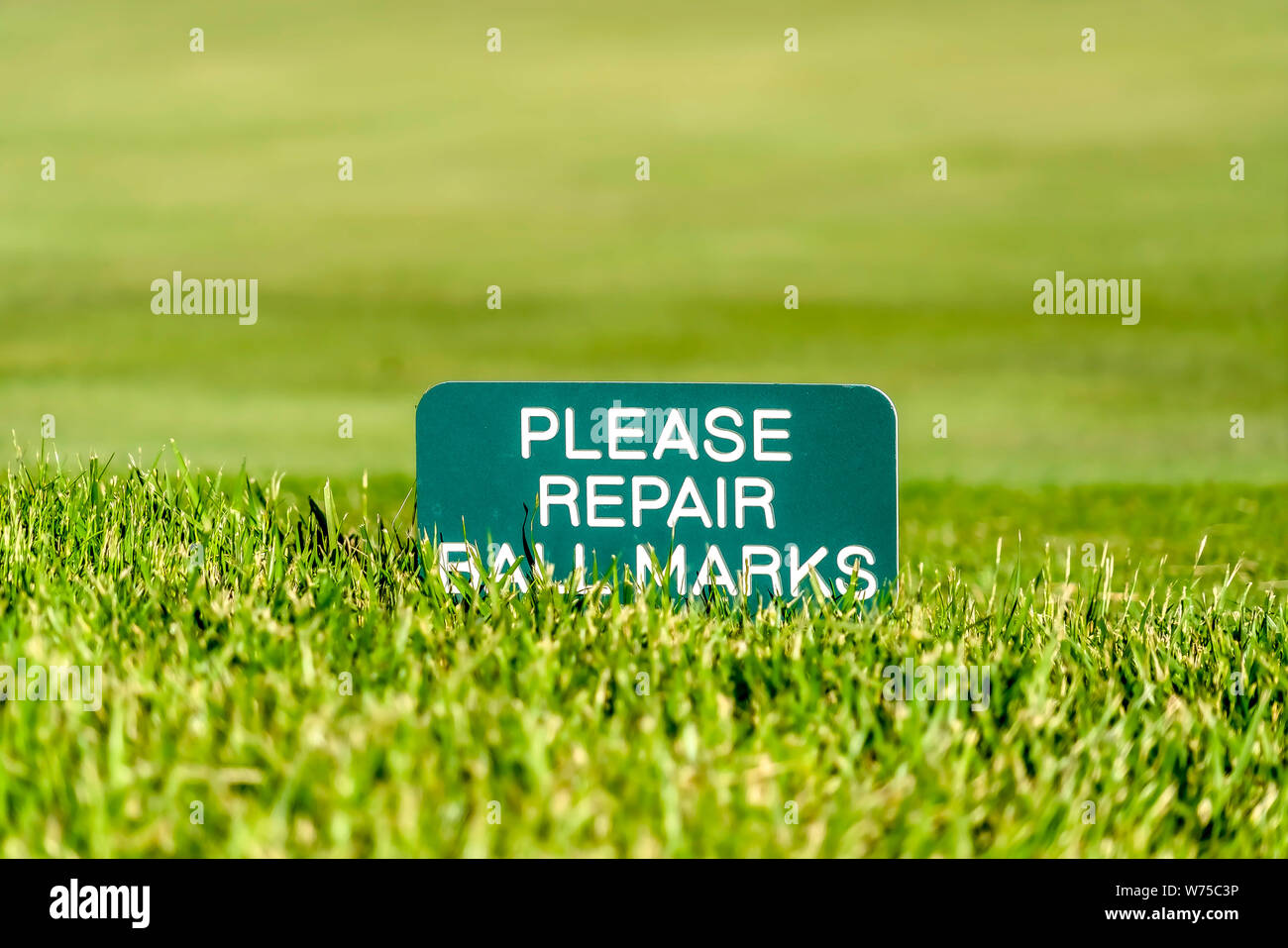 Close up of a golf course sign that reads Please Repair Ball Marks