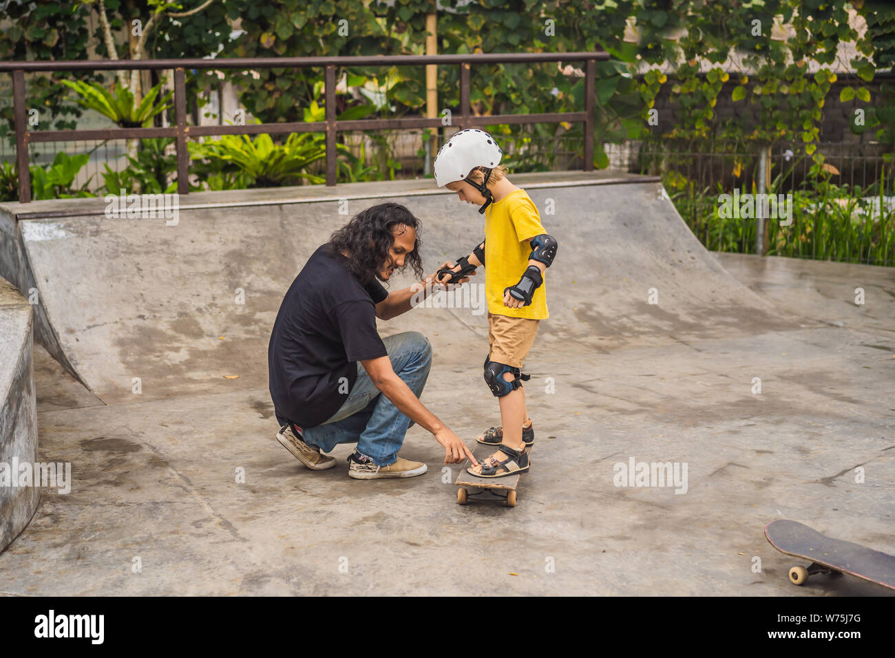 Athletic boy learns to skateboard with a trainer in a skate park. Children  education, sports Stock Photo - Alamy