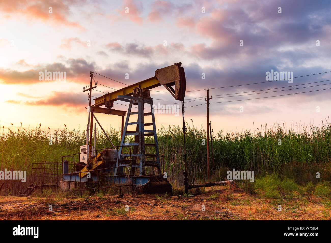 Oil rig pump against a colorful sunset sky Stock Photo