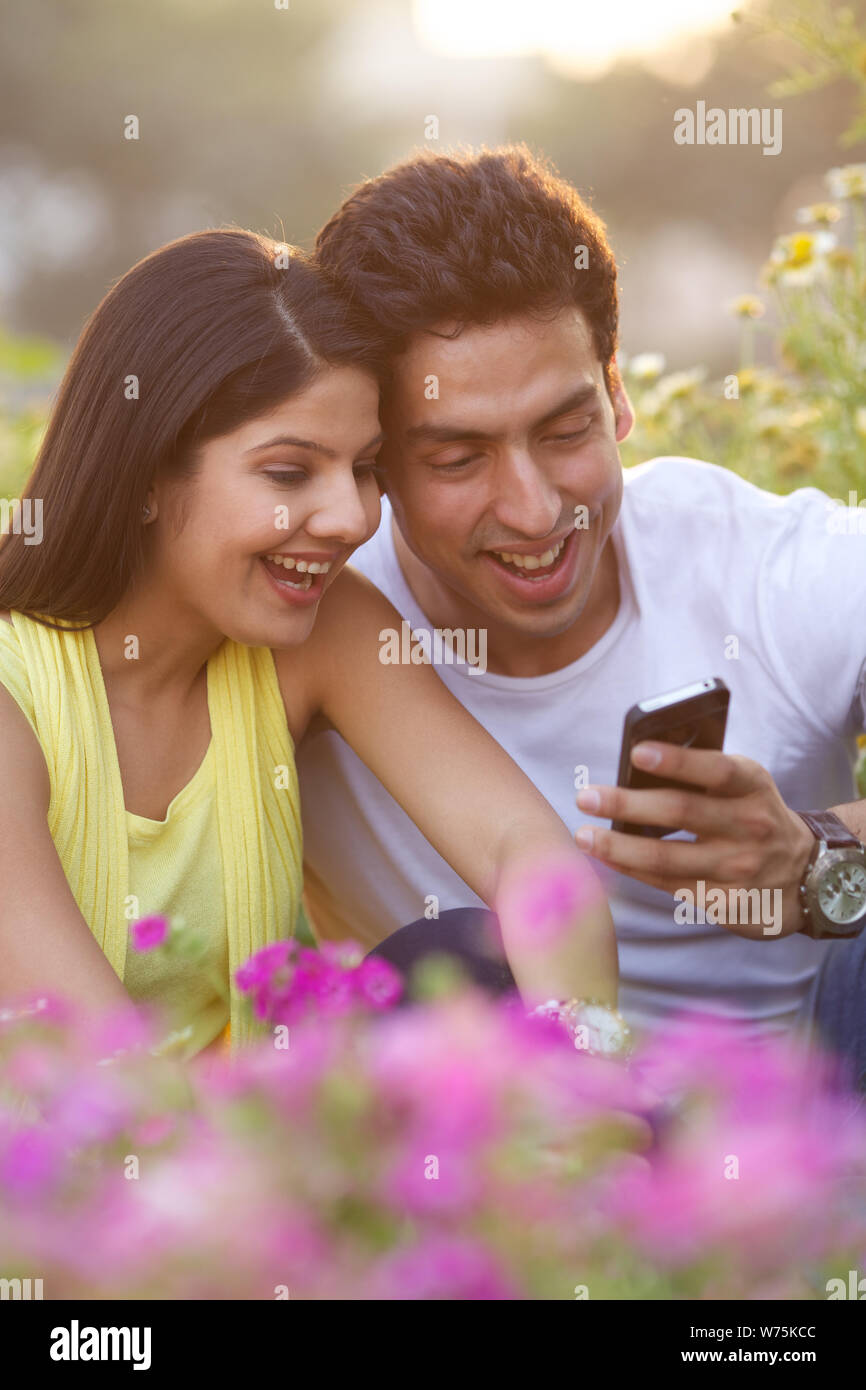 Couple using mobile phone in park Stock Photo