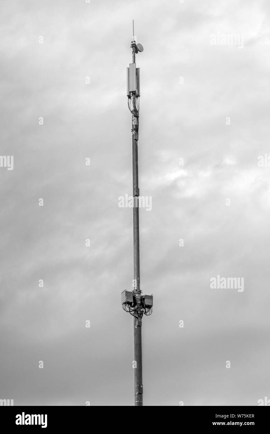 Telecommunication tower with antennas against grey sky background. Stock Photo