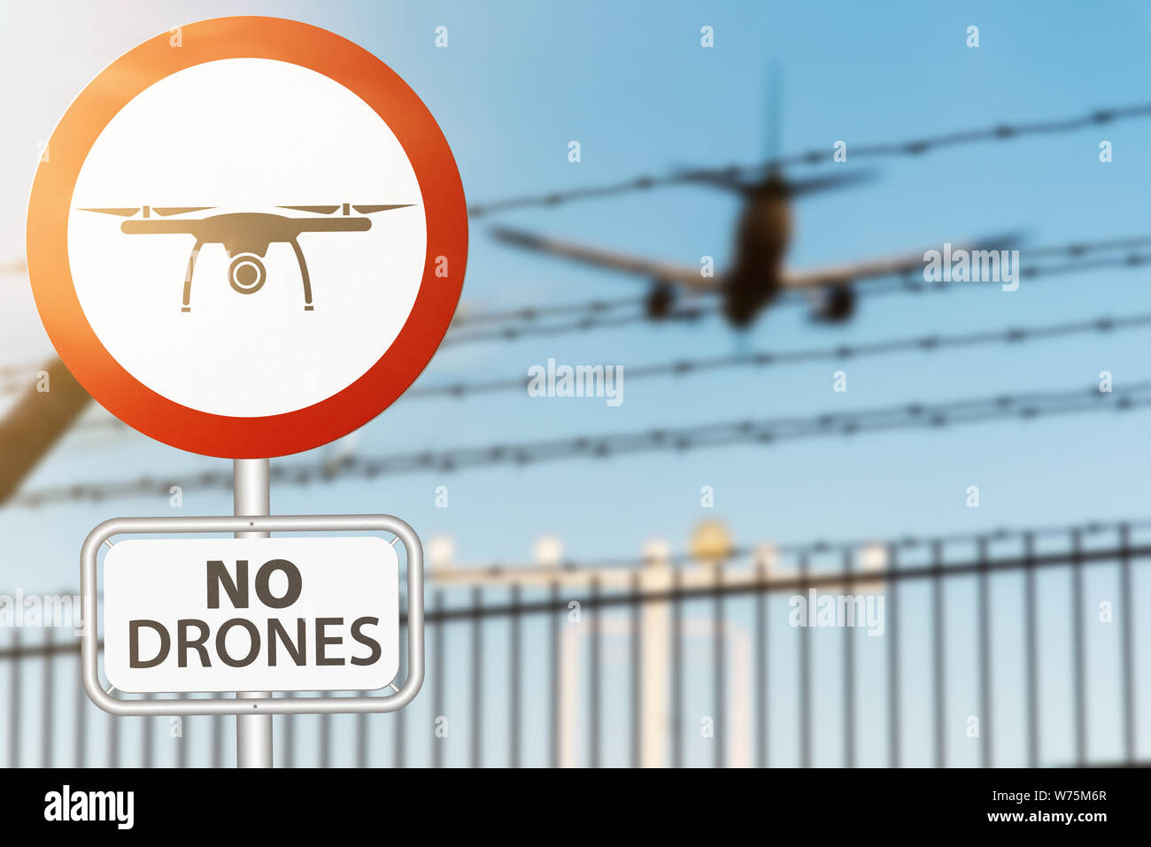 close-up of drone prohobition sign against security fence and airplane landing on airport Stock Photo