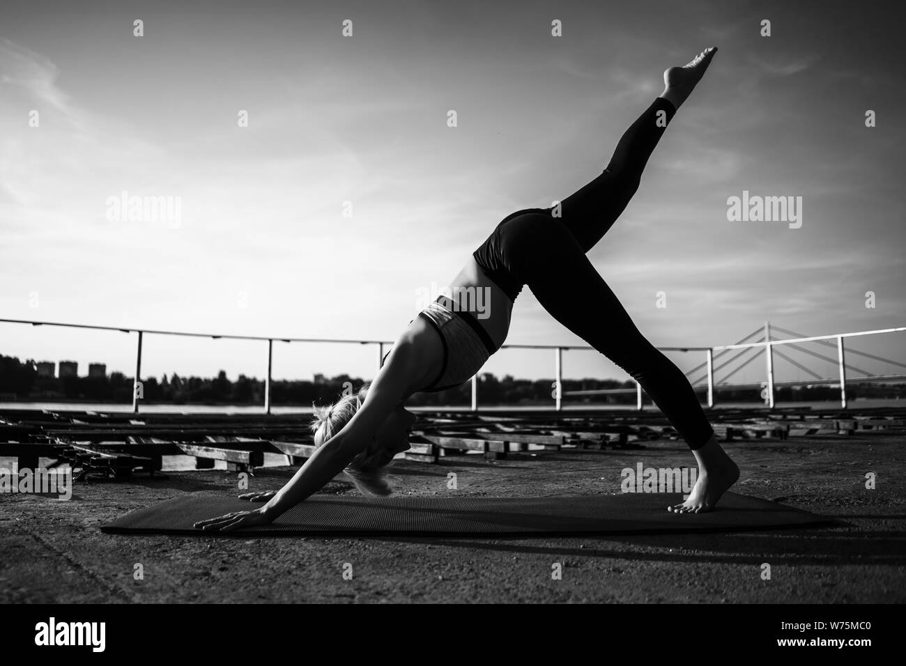 Woman practicing yoga on sunny day. Svanasana/One-Legged Downward-Facing Dog Pose Stock Photo