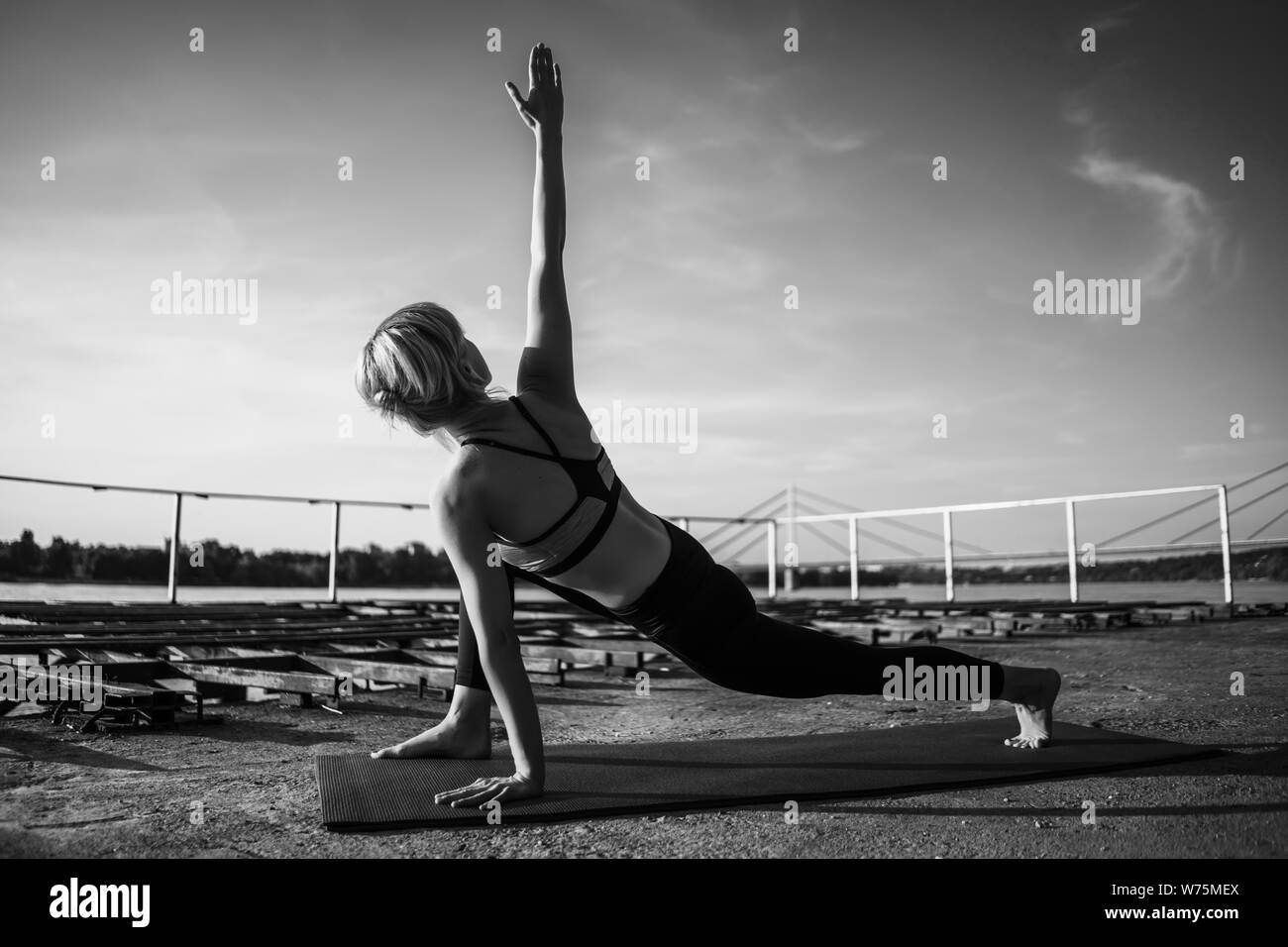 Woman practicing yoga on sunny day. Virabhadrasana, Rotated warrior pose Stock Photo
