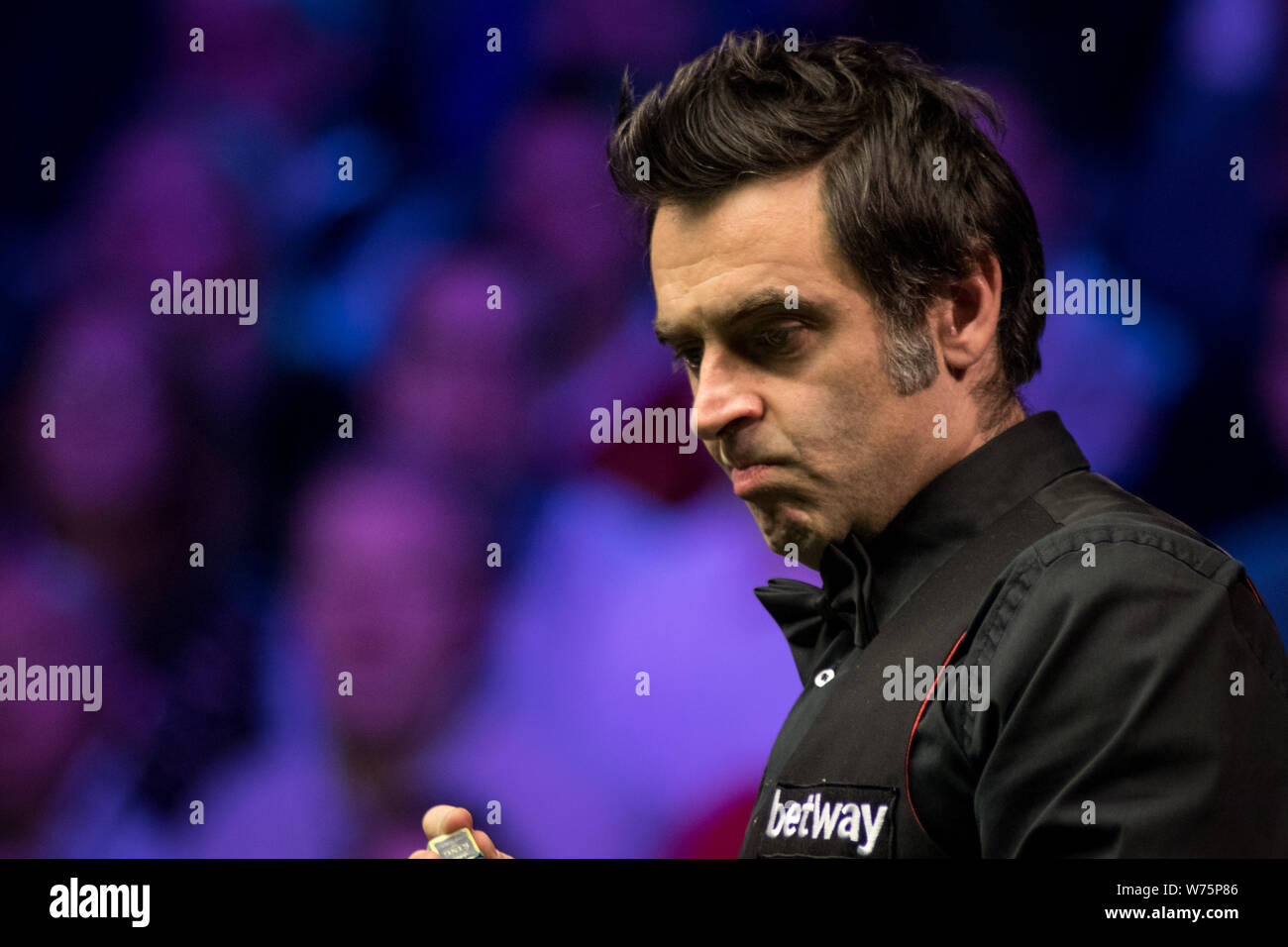Ronnie O'Sullivan of England chalks his cue as he considers a shot to Shaun Murphy of England in their final match during the 2017 Betway UK Champions Stock Photo