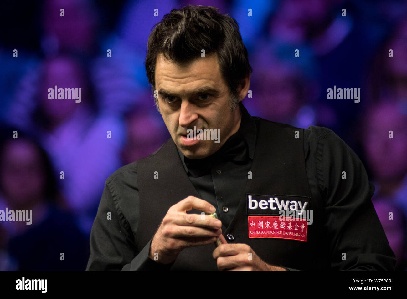 Ronnie O'Sullivan of England chalks his cue as he considers a shot to Shaun Murphy of England in their final match during the 2017 Betway UK Champions Stock Photo