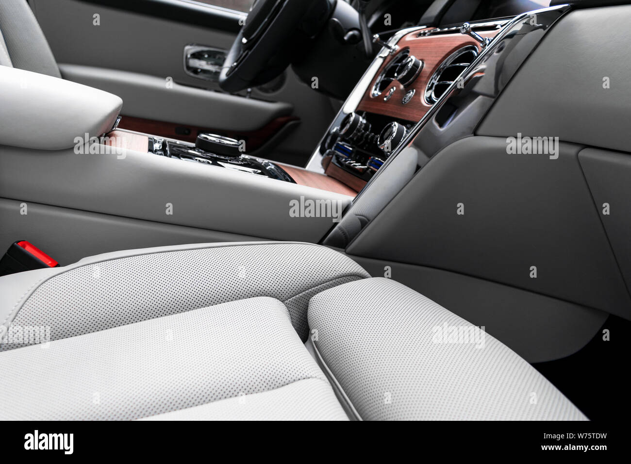 Modern luxury car white leather interior with natural wood panel. Part of leather car seat details with stitching. Interior of prestige modern car. Wh Stock Photo