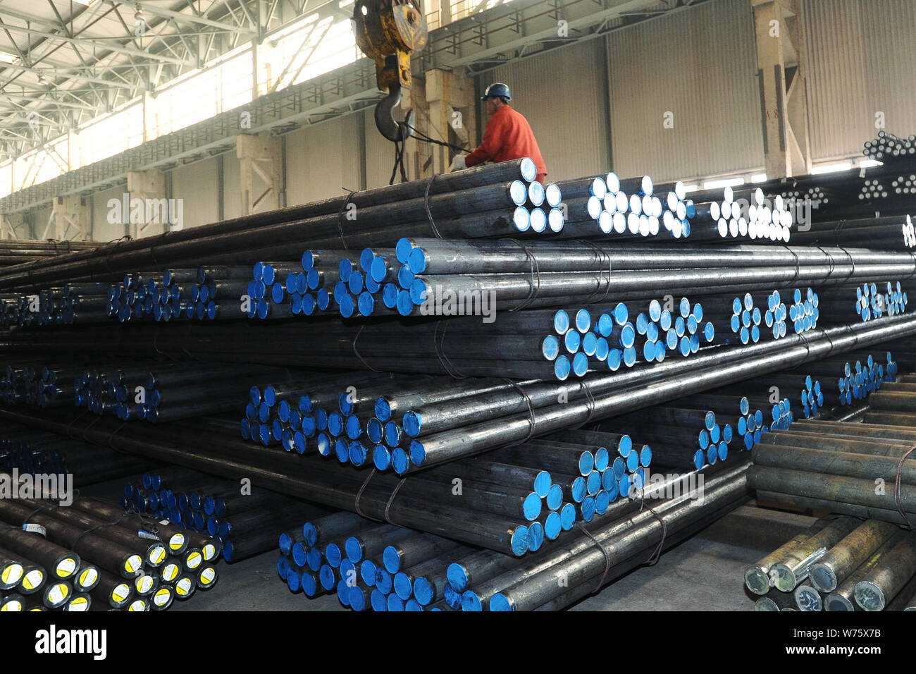 --FILE--A Chinese worker directs a crane to lift reinforcing steel rods ...