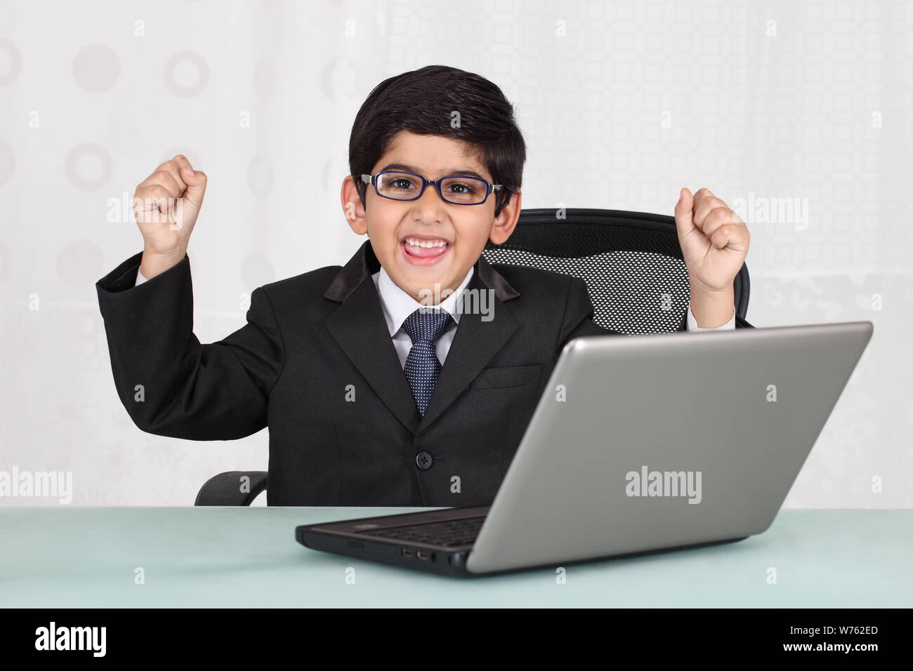 Boy pretending to be a businessman working on a laptop Stock Photo