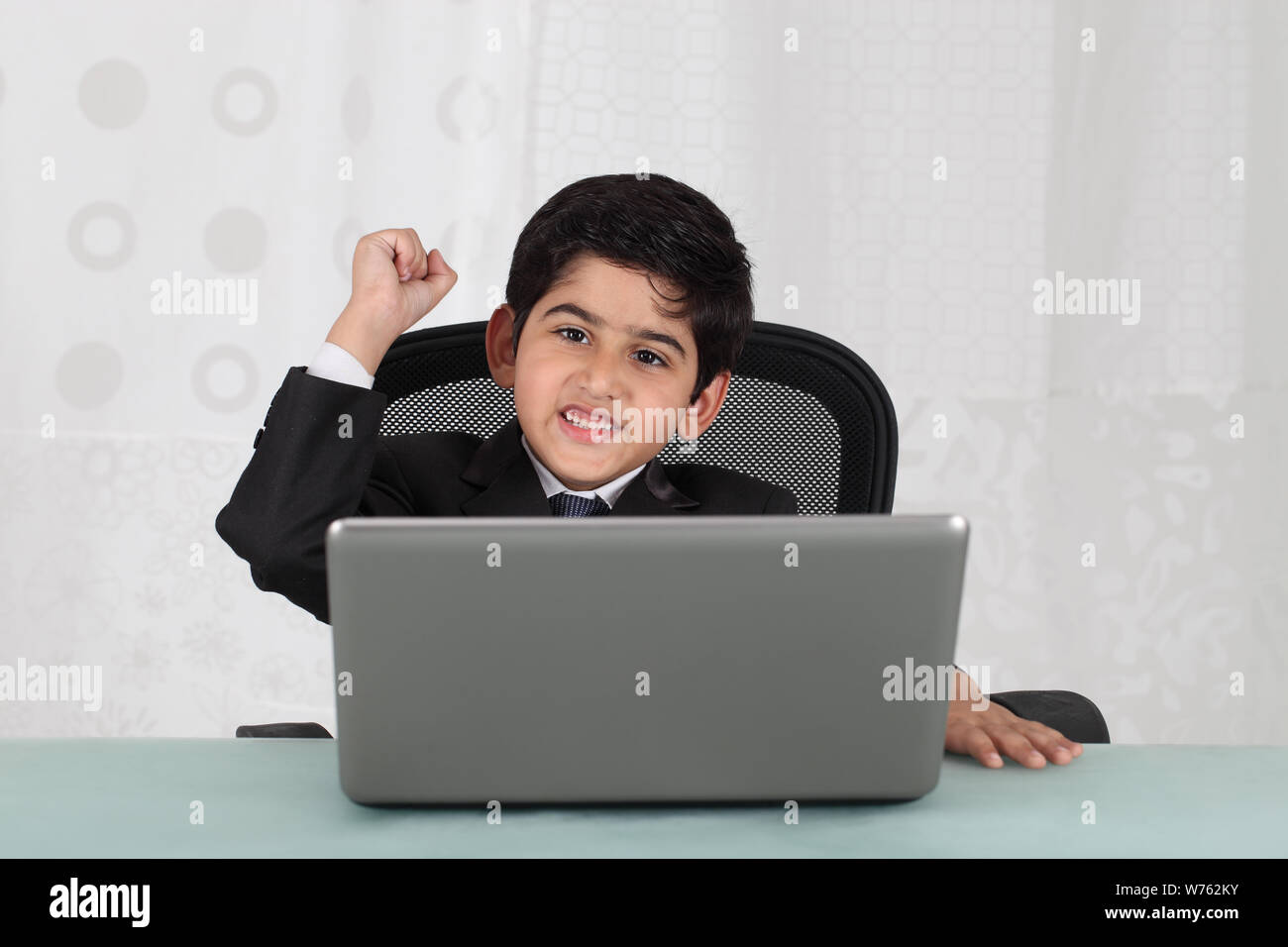 Boy pretending to be a businessman working on a laptop Stock Photo