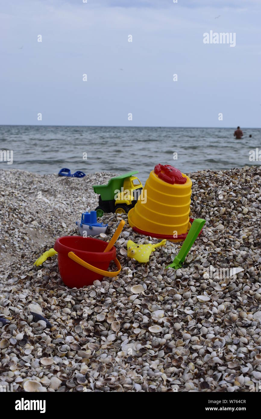 Child's bucket, spade and other toys on tropical beach against sea and ...