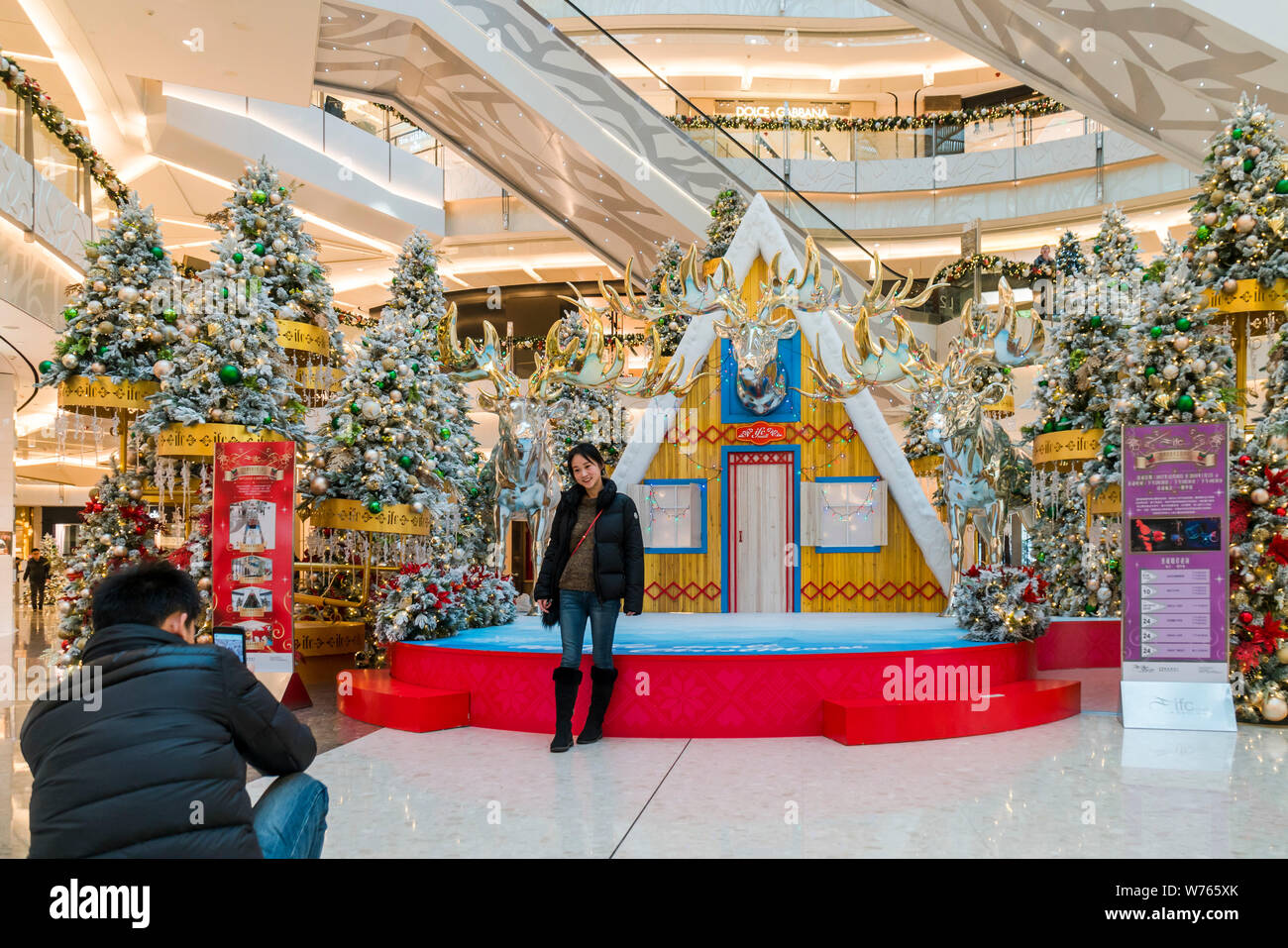 A visitor takes photos with a moose manor house on display for the upcoming Christmas at the Shanghai International Finance Centre (IFC) in Shanghai, Stock Photo