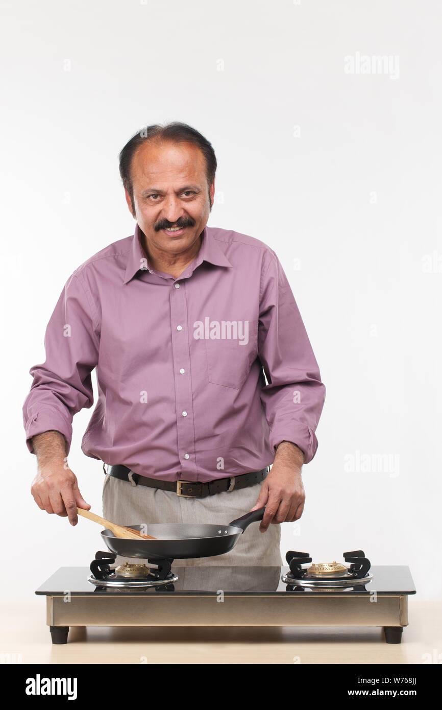 Mature man cooking food in kitchen Stock Photo