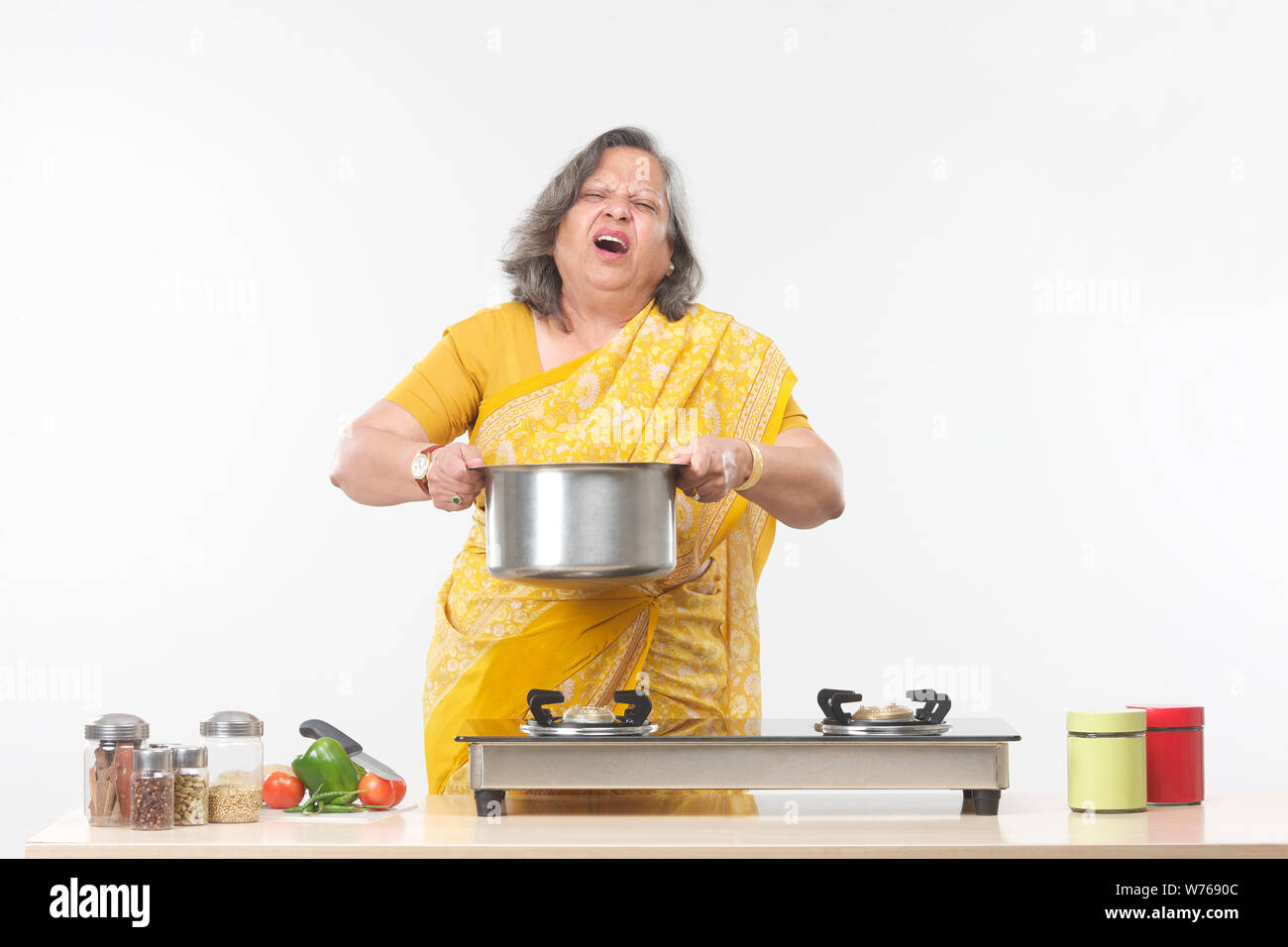 Old woman suffering from pain while cooking food in kitchen Stock Photo