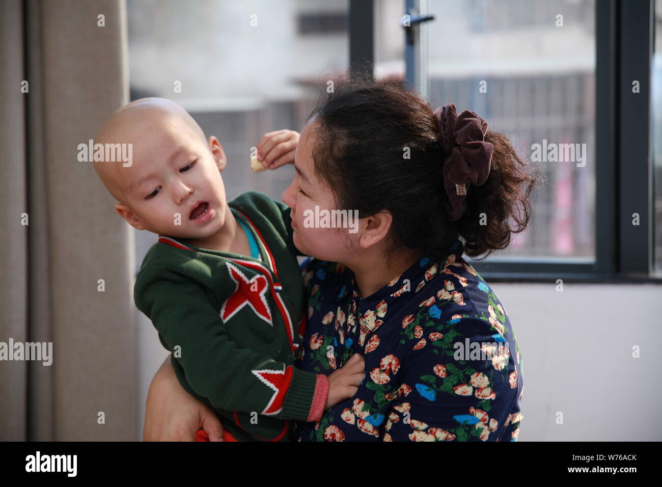 Three-year-old Uyghur boy diagnosed with rhabdomyosarcoma hugs his mother in Guangzhou city, south China's Guangdong province, 2 December 2017.   Thre Stock Photo