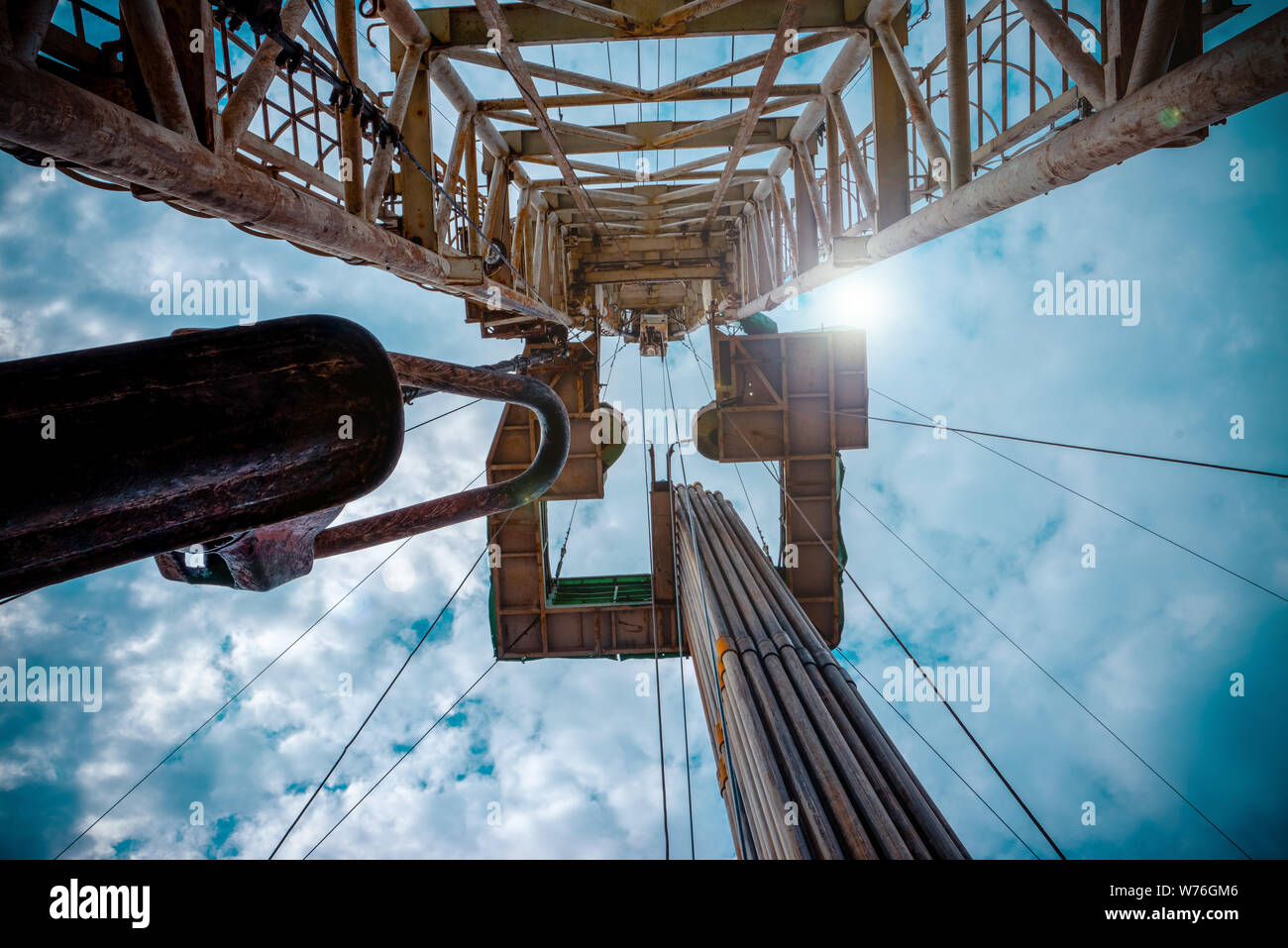 Oil and Gas Drilling Rig onshore dessert with dramatic cloudscape. Oil drilling rig operation on the oil platform in oil and gas industry. Stock Photo
