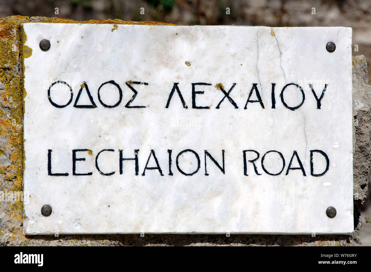 Greece. Ancient Corinth. Bilingual inscription in Greek and English, regarding the Lechaion road. Marble-paved road to the port of Lechaion. Peloponnese. Stock Photo