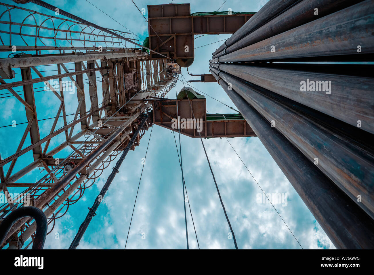 Oil and Gas Drilling Rig onshore dessert with dramatic cloudscape. Oil drilling rig operation on the oil platform in oil and gas industry. Stock Photo