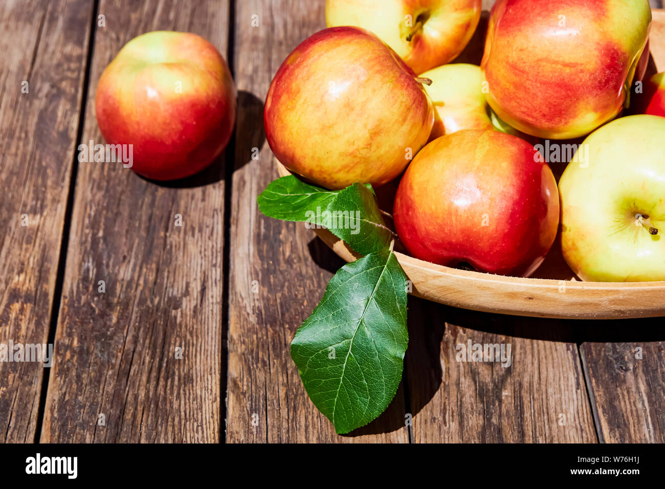 Fresh red apples with green leaves on a wooden old table. On a wooden background. Free space for text. soft focus Stock Photo