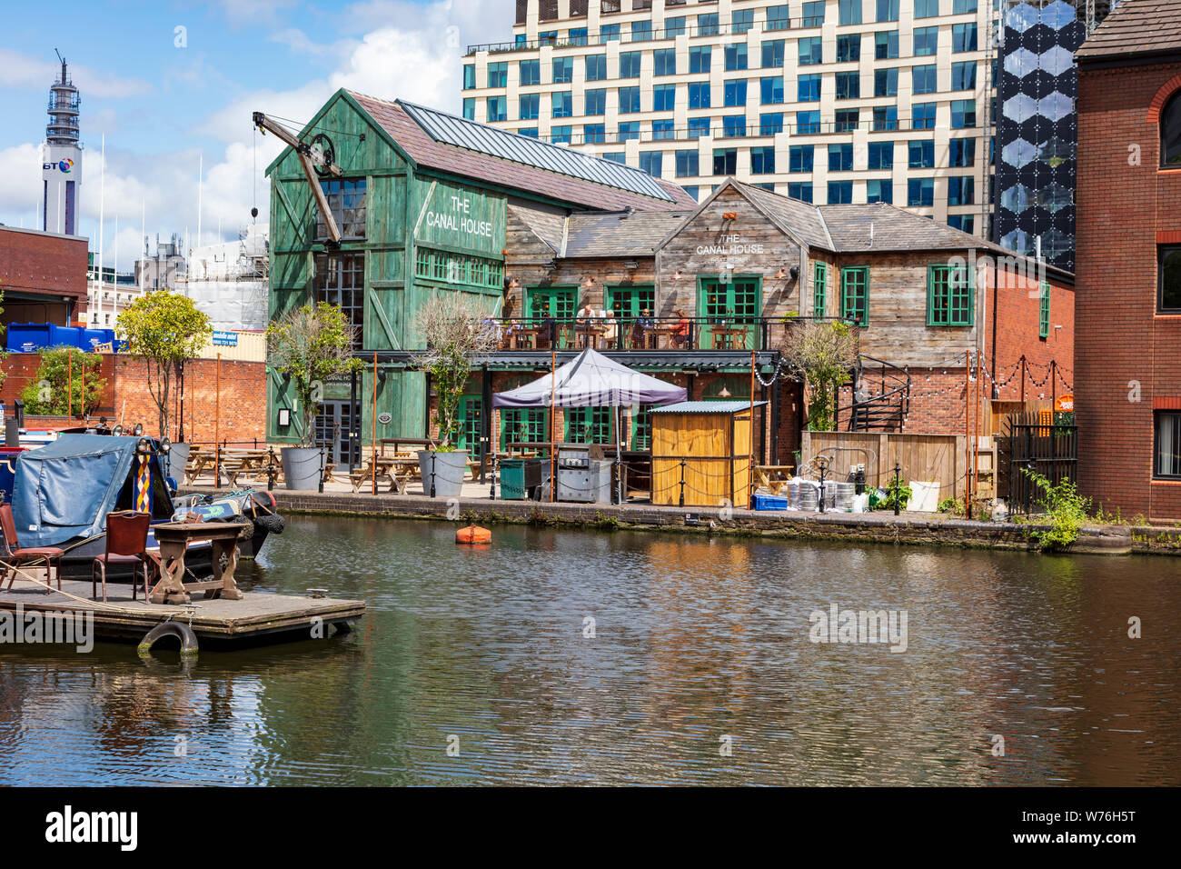 A view across Canal Street Basin on the New Mainline Canal towards The Canal House pub with drinkers on the balcony and moored Narrow Boats, Birmingham UK Stock Photo