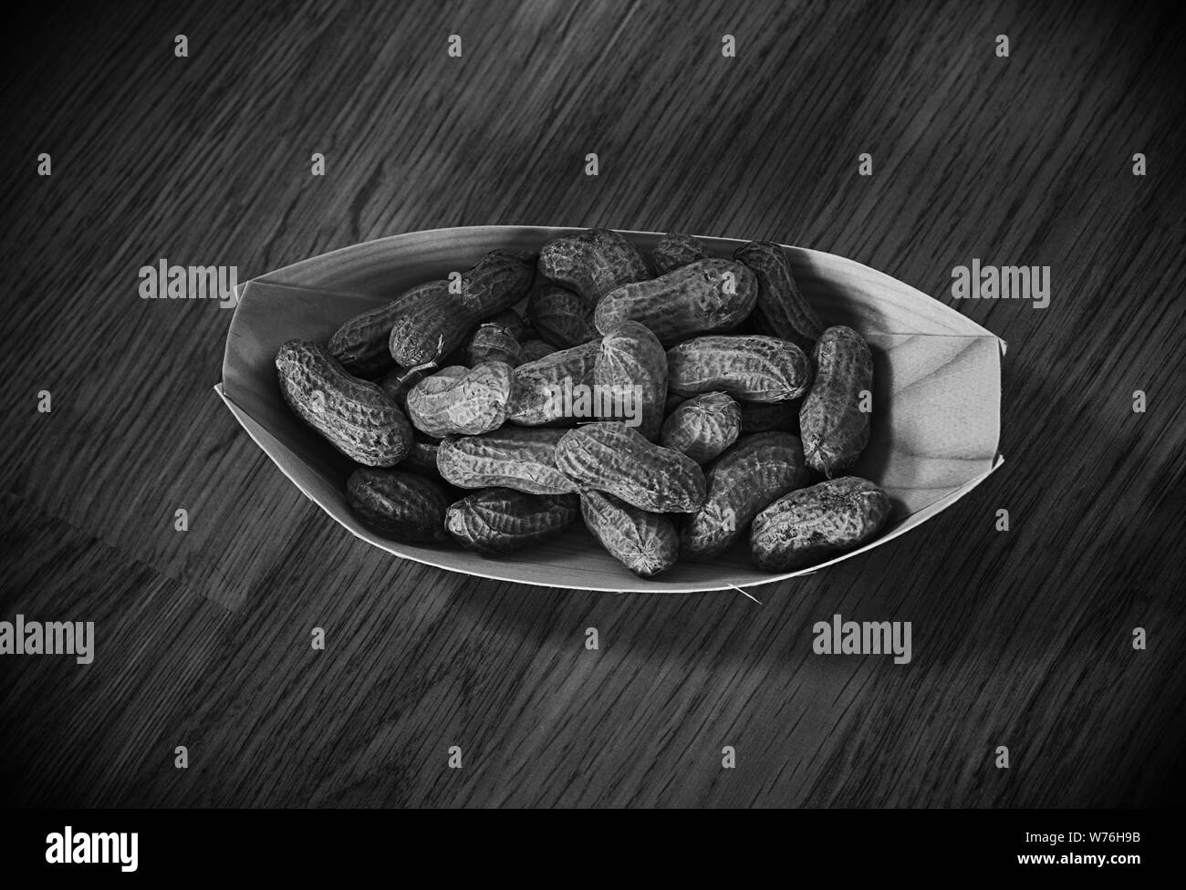 Peanuts in a eco, wooden container isolated on wooden background. Black and white photo Stock Photo